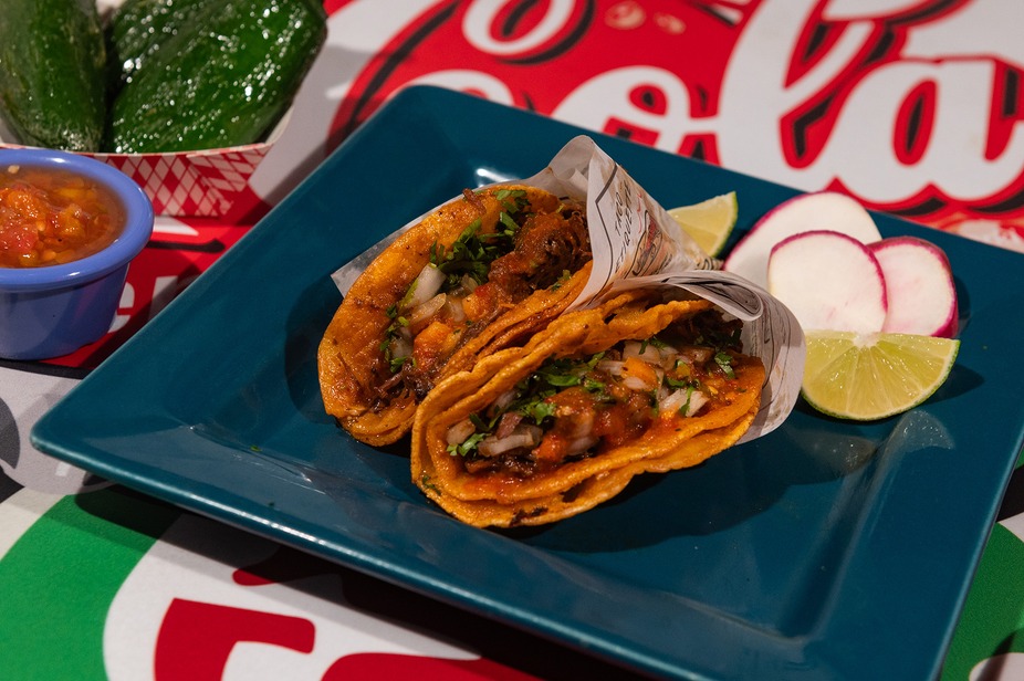 Birria tacos plated with lime, radish and salsa on a teal plate